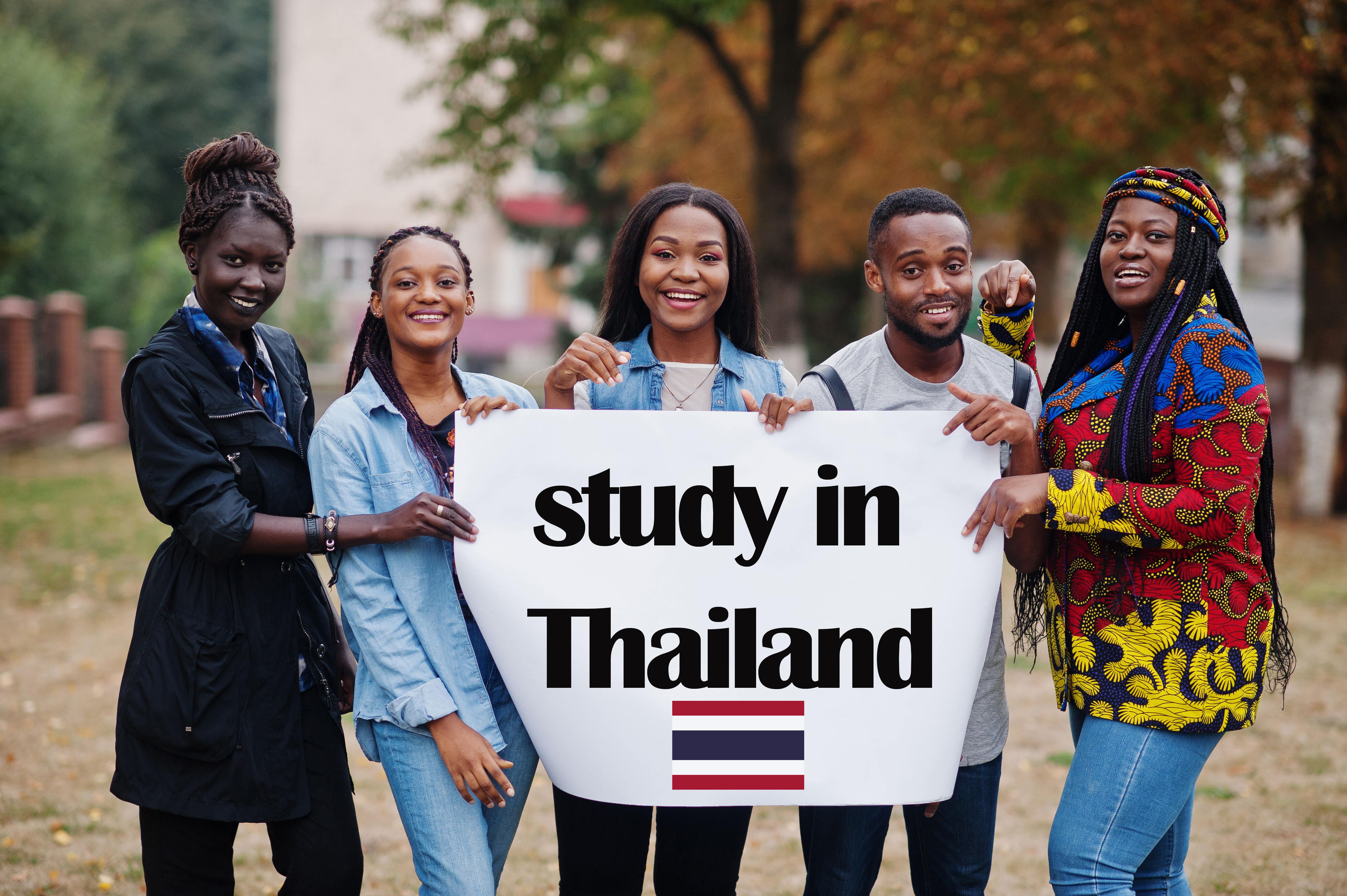 Study in Thailand. Group of five african college students on campus at university yard hold white blank. Abroad countries for student concept.