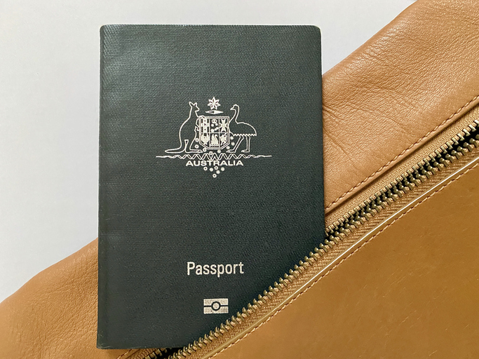 Closeup photo of an Australian passport just inside the zippered pocket of a tan leather handbag